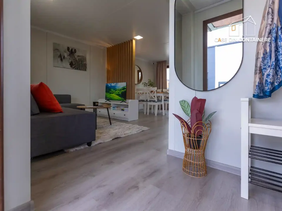 Interior casa modulara cu canapea gri si oglinda rotunda pe perete - Case din containere